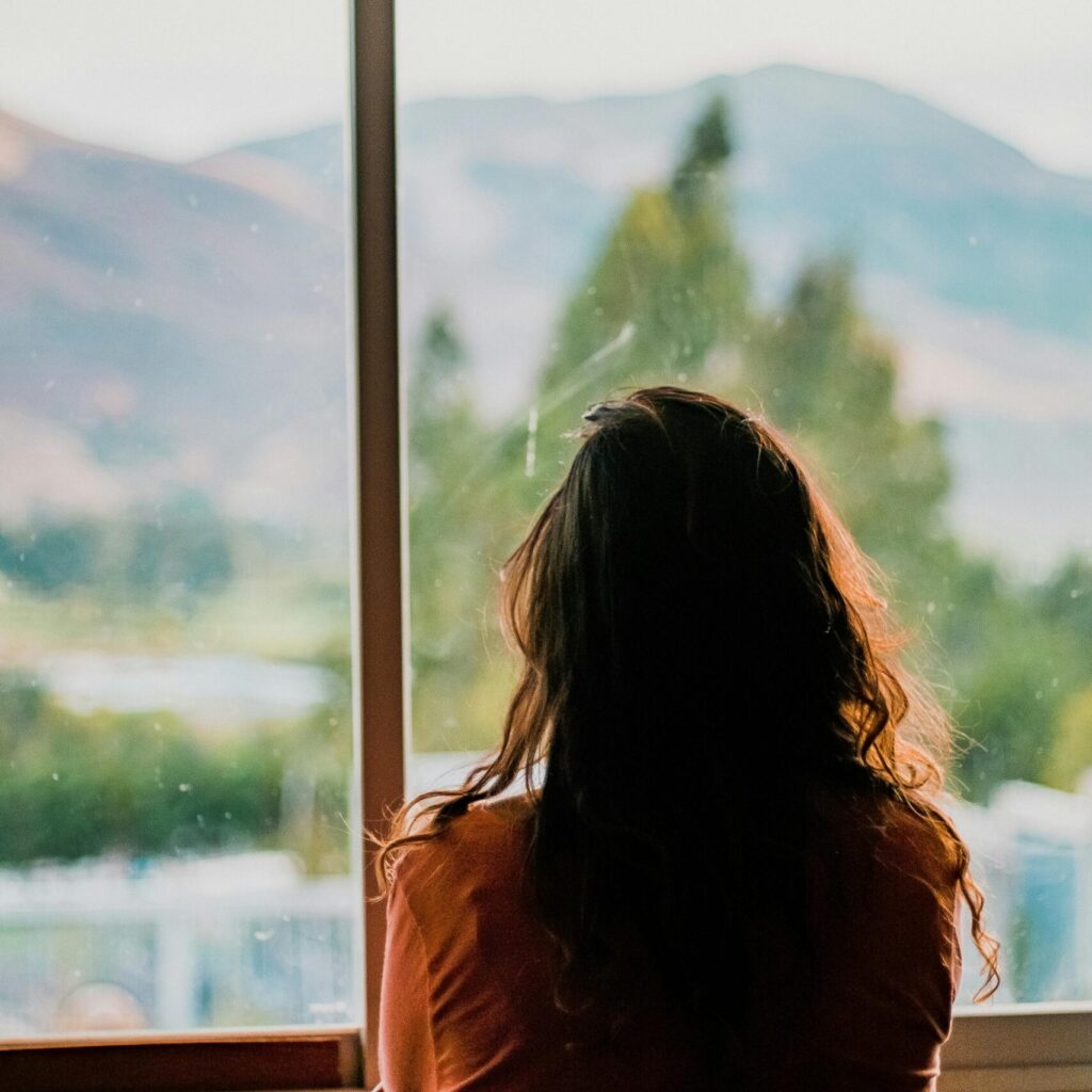 Silhouette of a woman looking out a window at a scenic mountain view in Cajamarca, Peru.