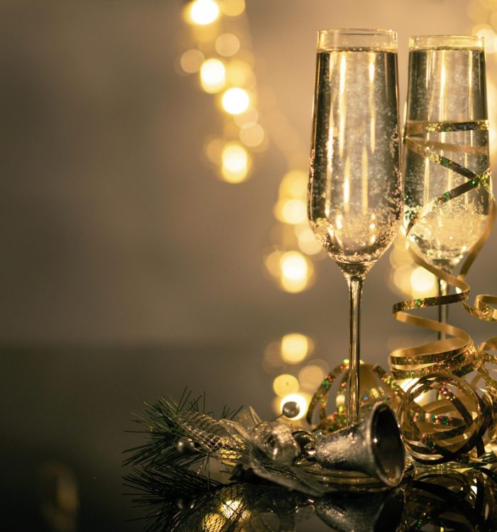 Champagne glasses with ribbons against festive bokeh lights.